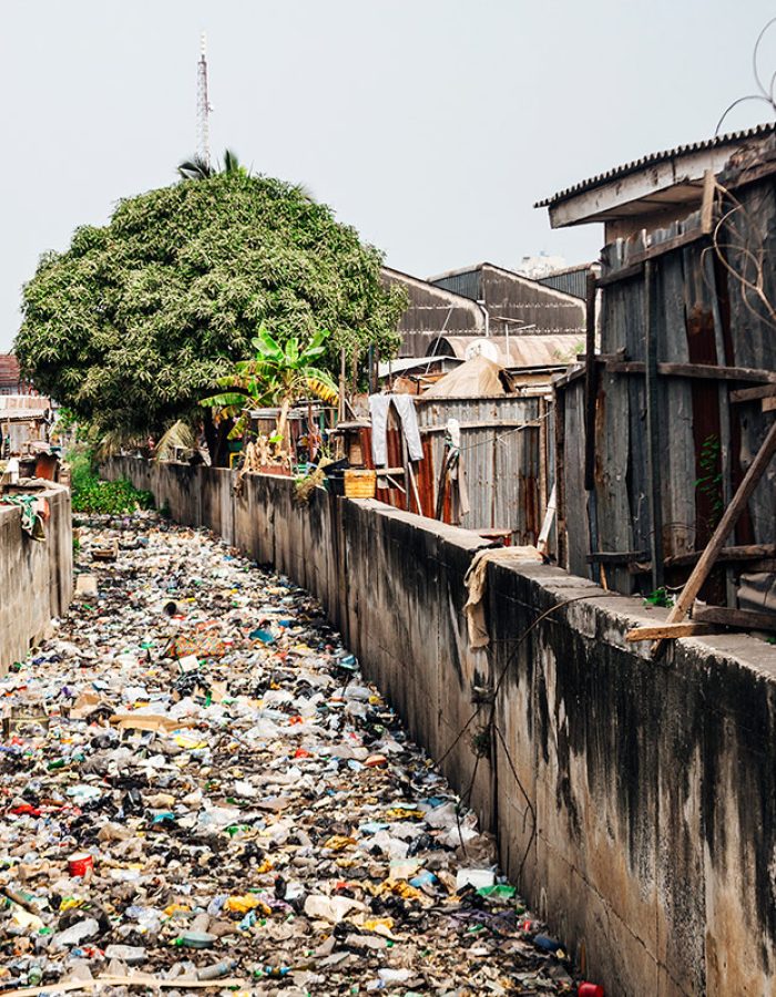 Slum streets, lots of garbage in canal.